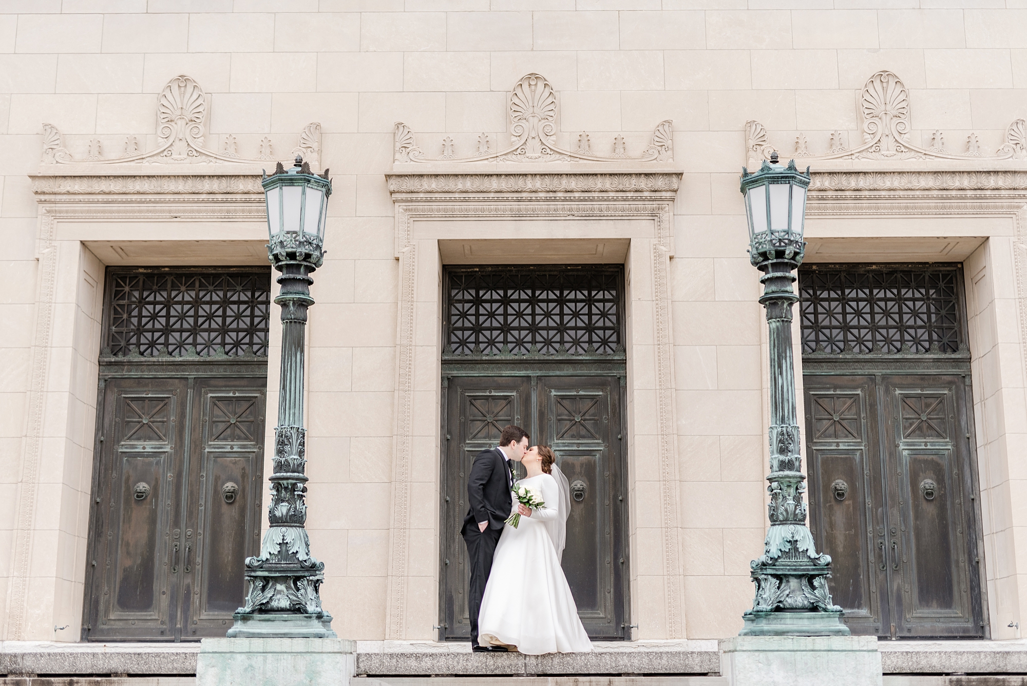 bride and groom kiss in front of doors at Dayton Masonic Center