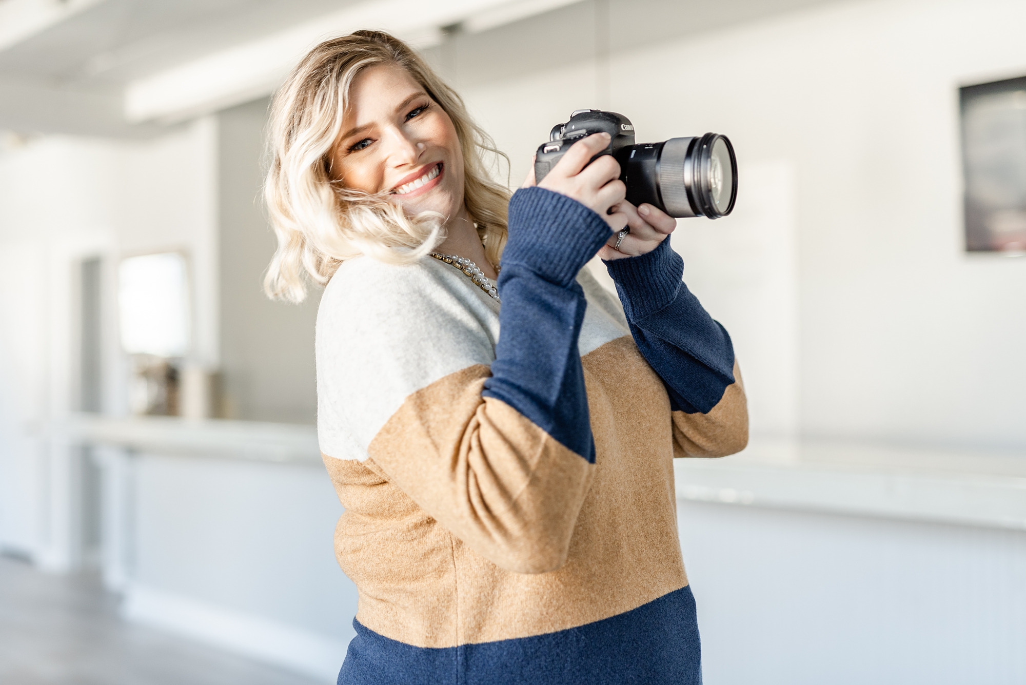 photographer holds camera in sweater during NC branding session