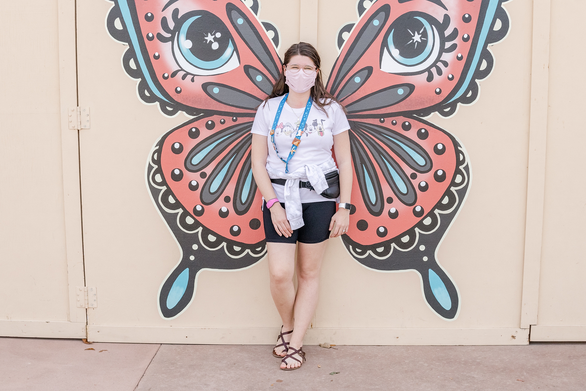 woman poses in front of butterfly mural at Epcot 