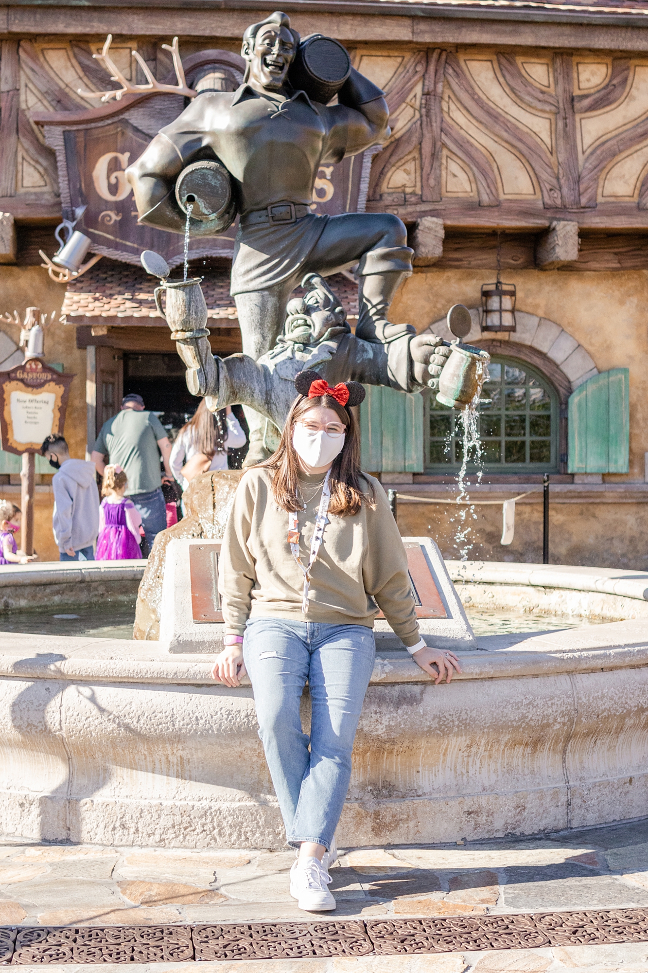 woman poses on edge of Gaston's Fountain at Walt Disney World trip 