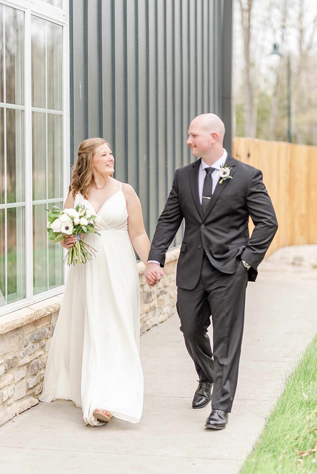 bride and groom hold hands walking outside The Estate at New Albany