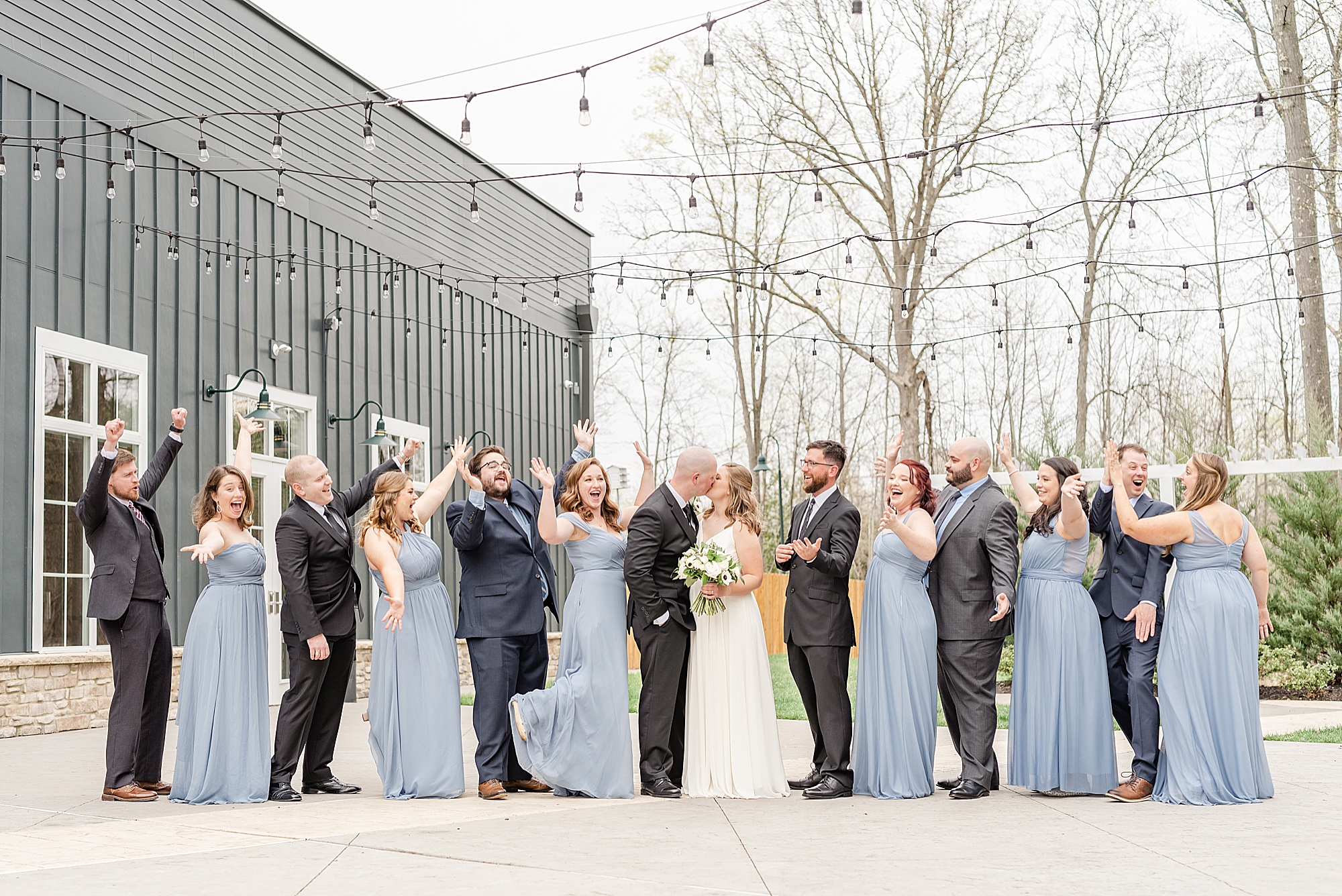 bride and groom kiss while bridal party cheers