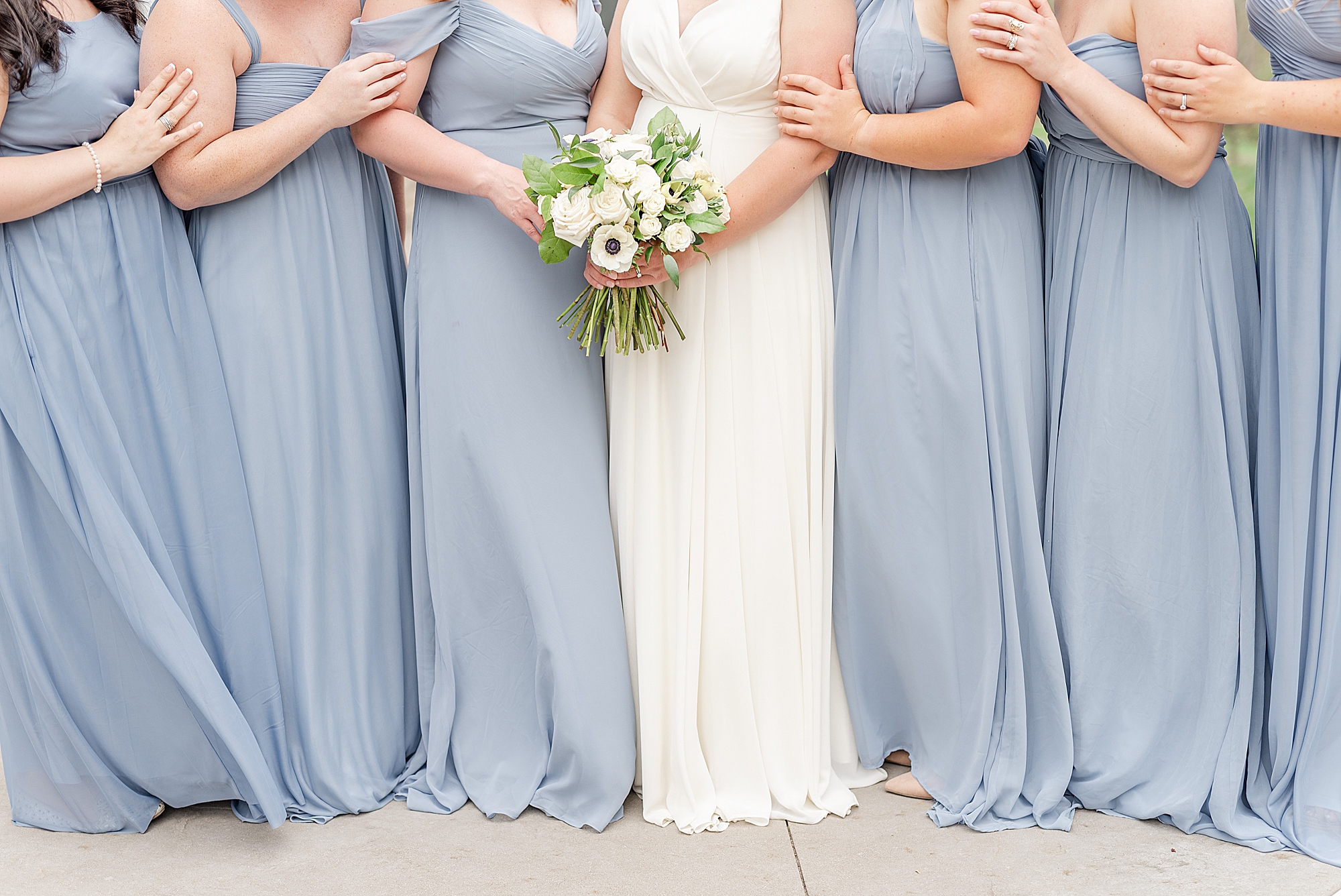 bride poses with bridesmaids in light blue dresses