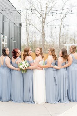 bridesmaids hug bride and look over shoulders during spring wedding at The Estate at New Albany