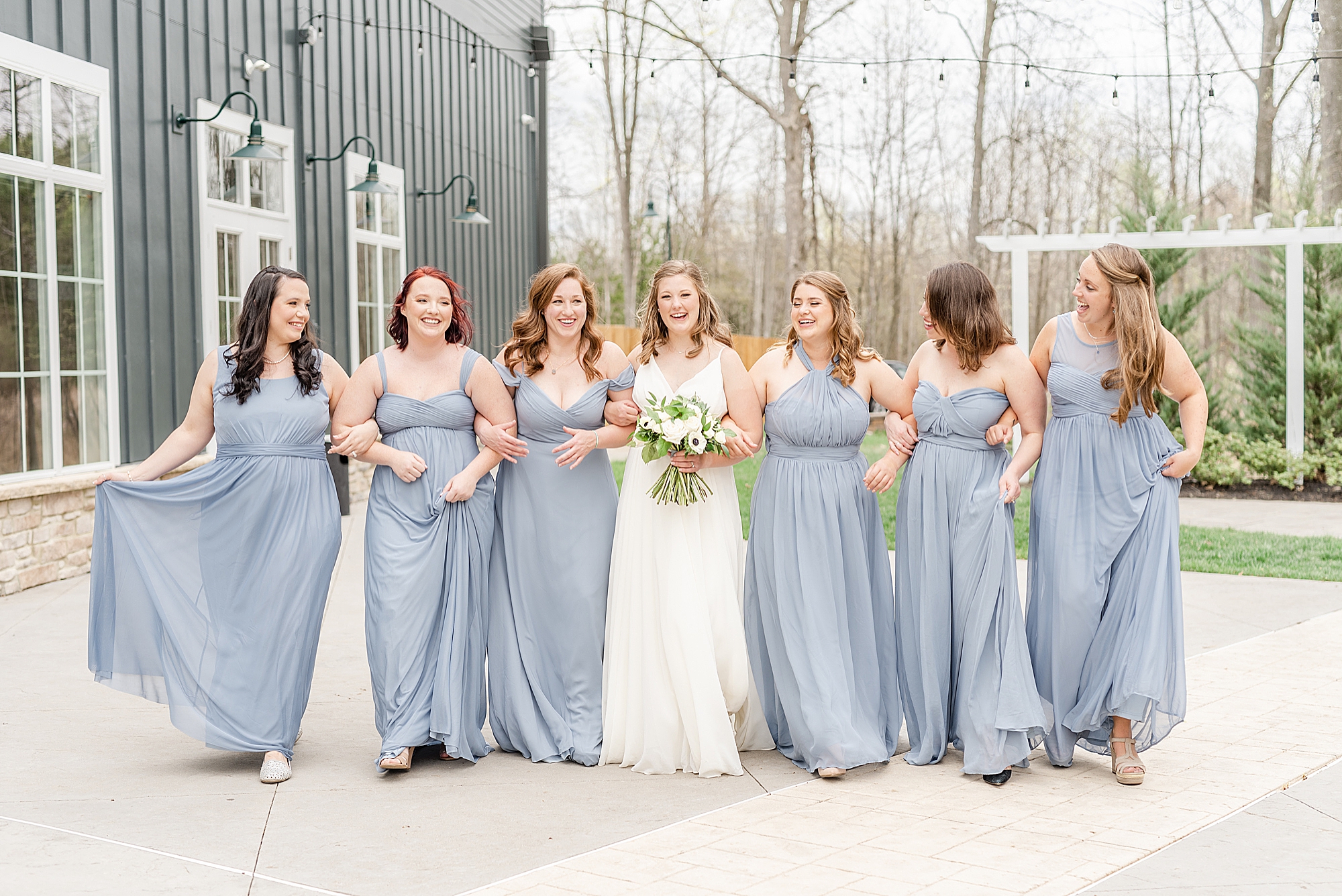bride walks outside The Estate at New Albany with bridesmaids in light blue gowns
