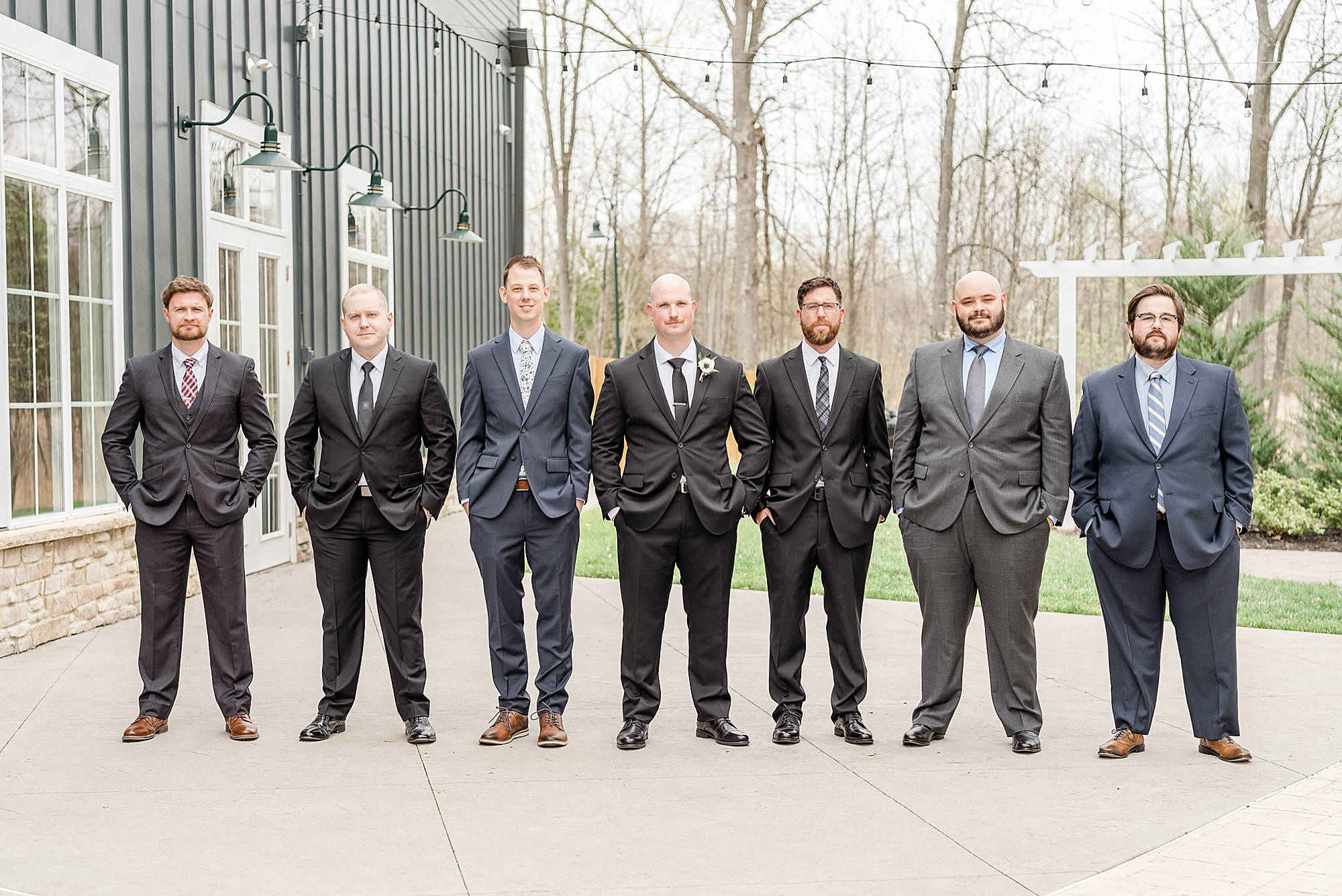 groom poses with groomsmen pose outside Ohio wedding venue