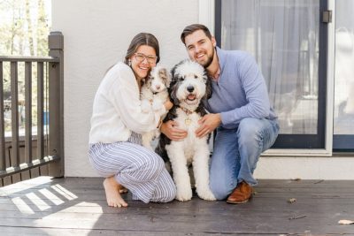 dog parents pose with two sheepadoodles