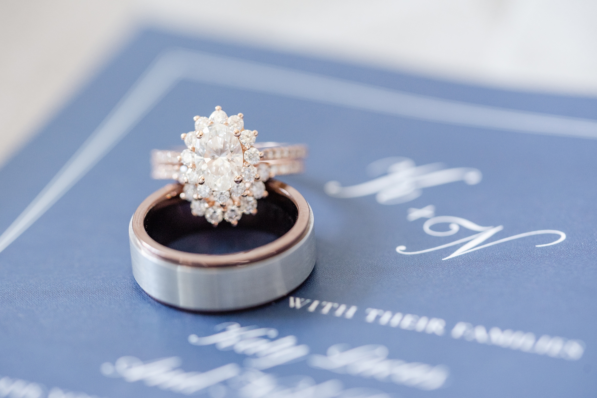 bride and groom's wedding rings sit on blue invitation