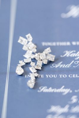 bride's earrings rest on blue invitation suite