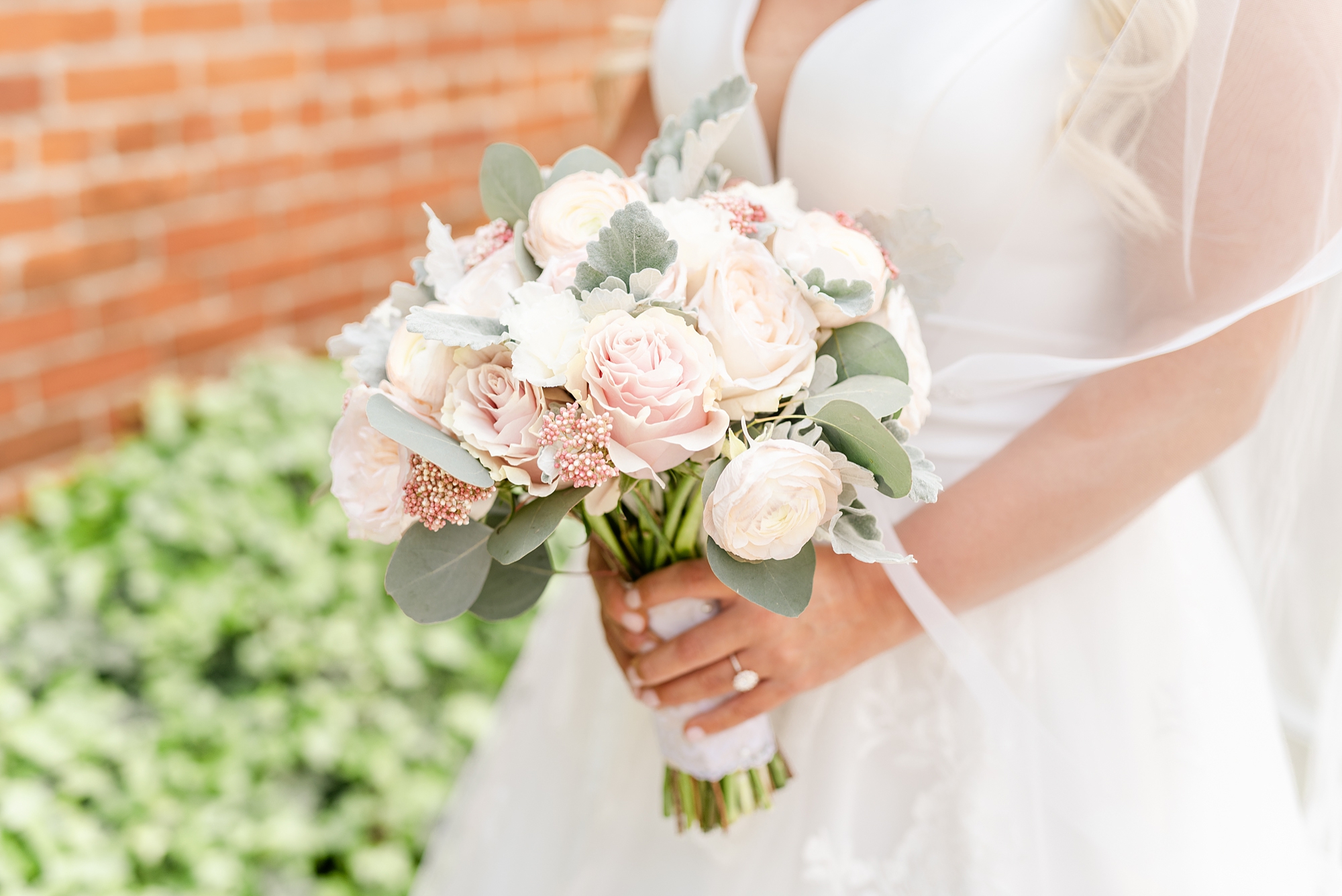 bride holds bouquet of white and ivory roses