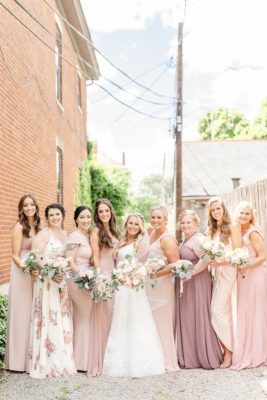 bride poses with bridesmaids in mismatched pink gowns