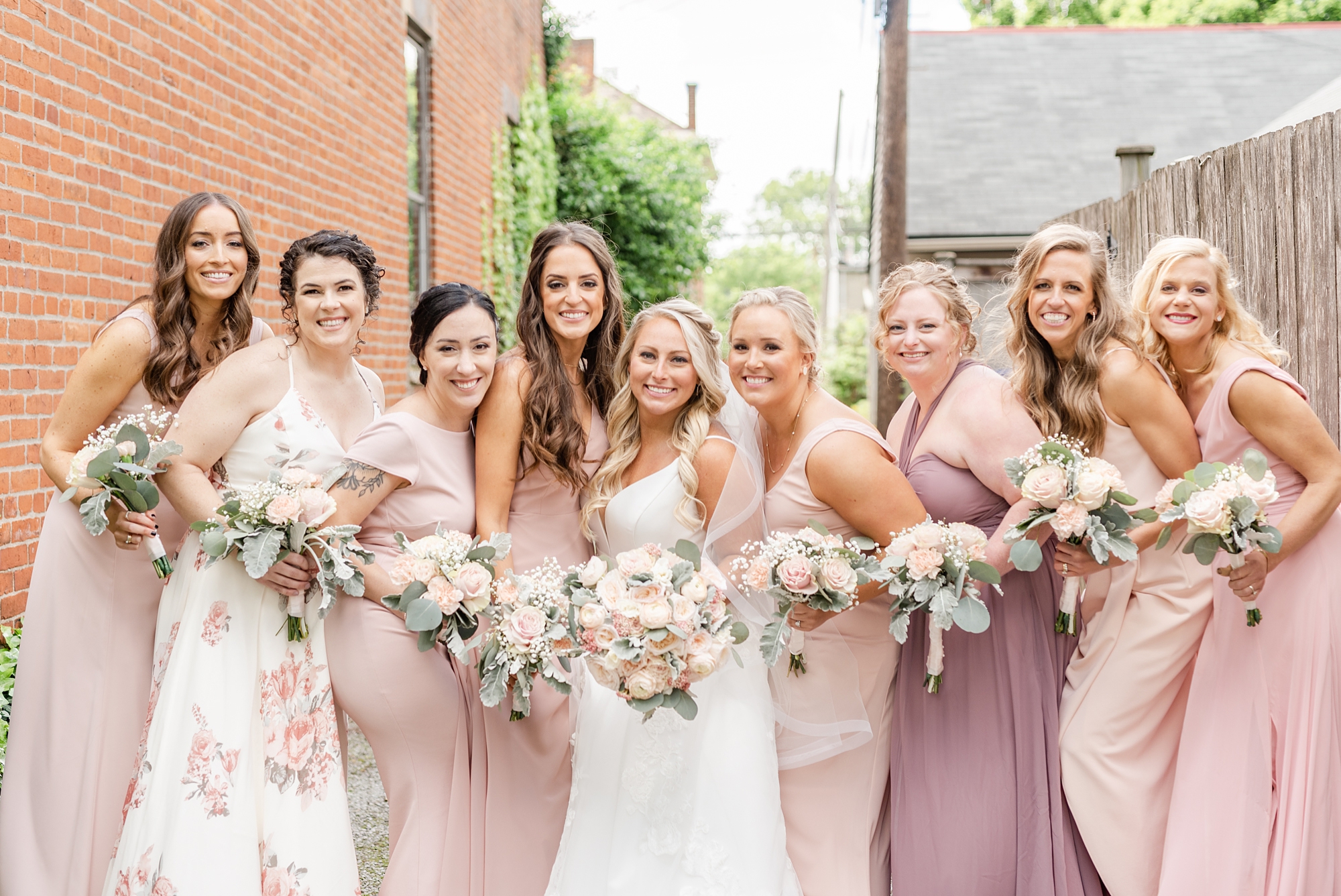 bride poses with bridesmaids in pink gowns