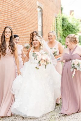 bride laughs and walks with bridesmaids in pink dresses