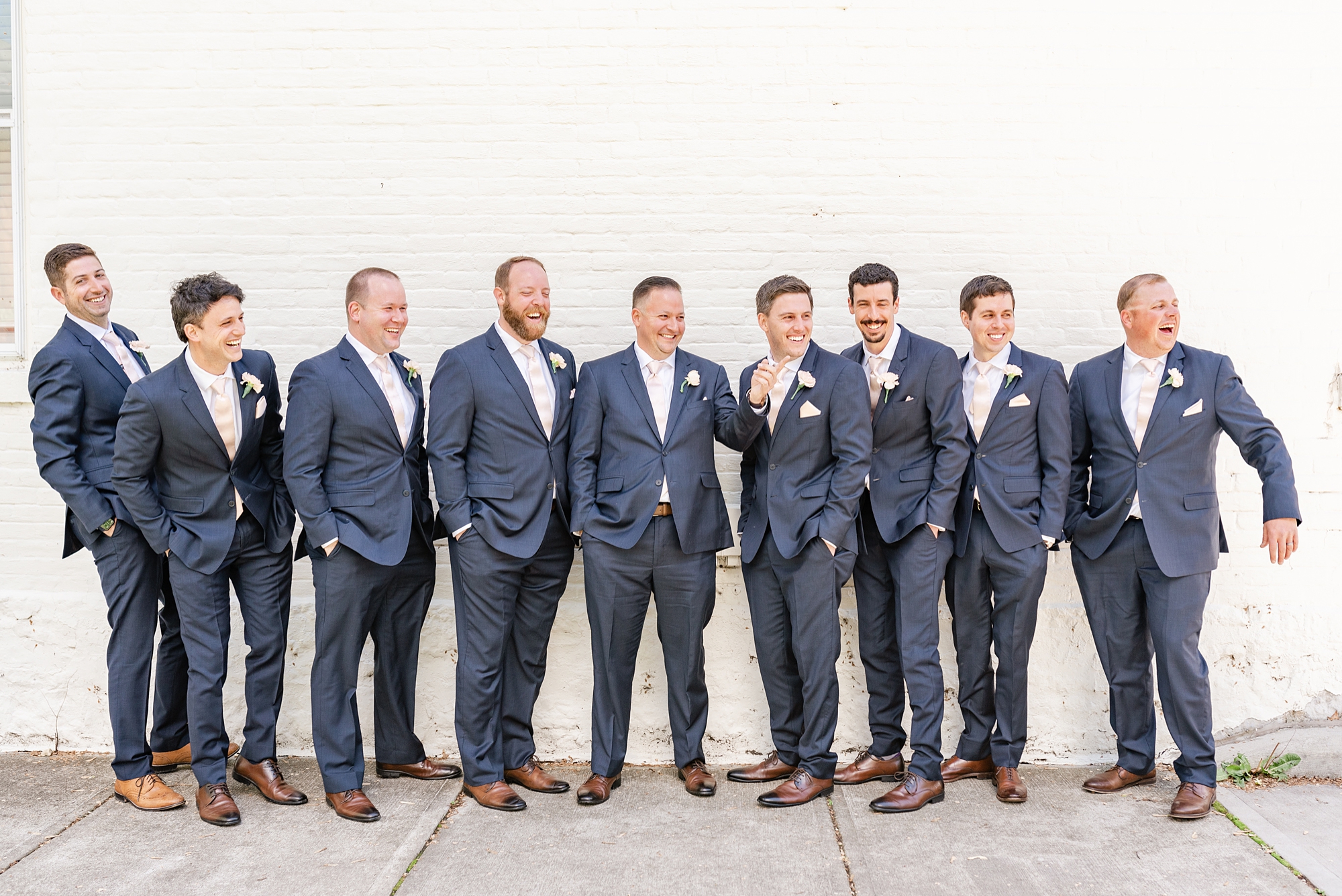groom and groomsmen pose by white wall in Columbus OH