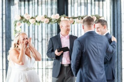 officiant talks during High Line Car House wedding ceremony by floral arch