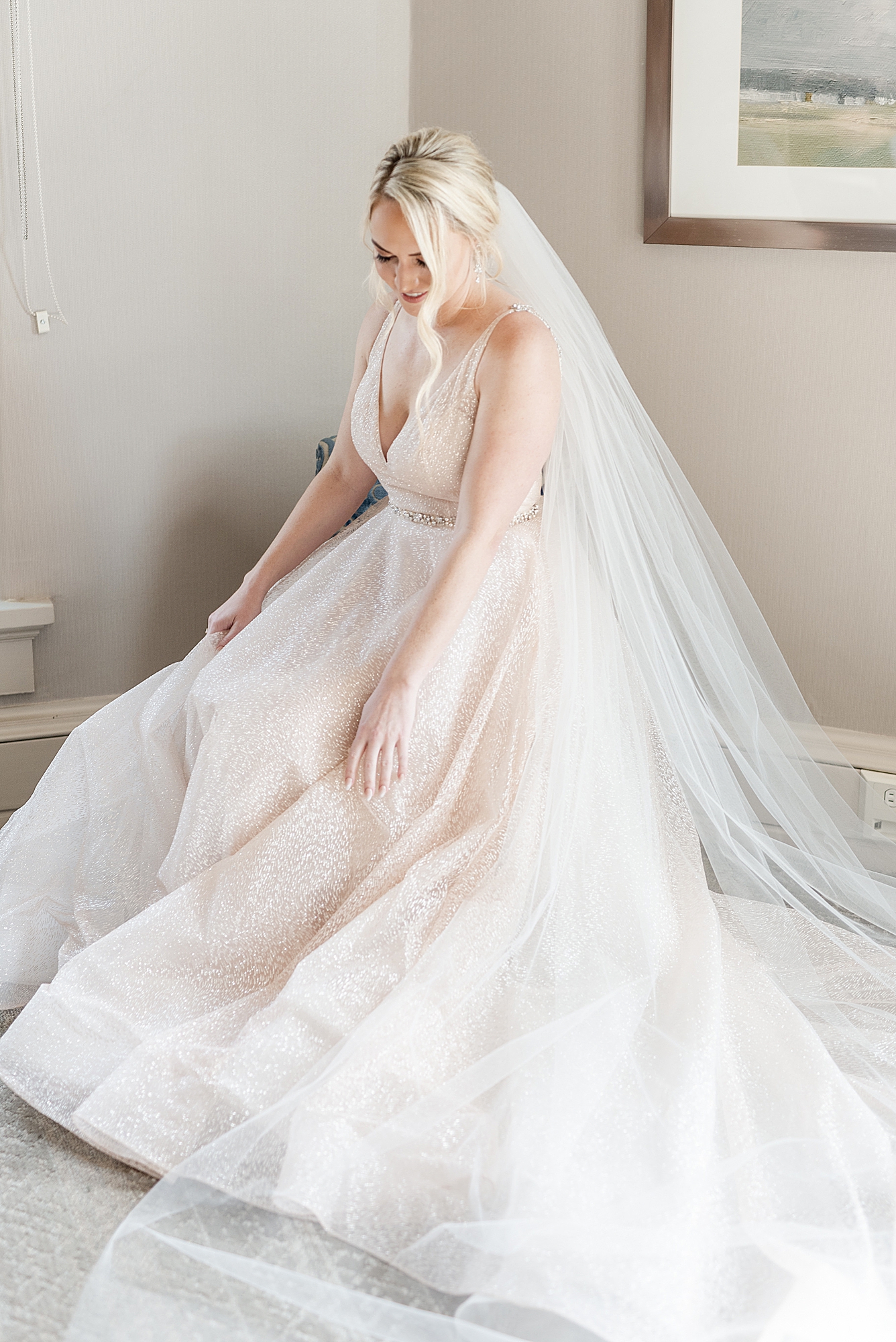 bride sits and adjusts blush wedding dress