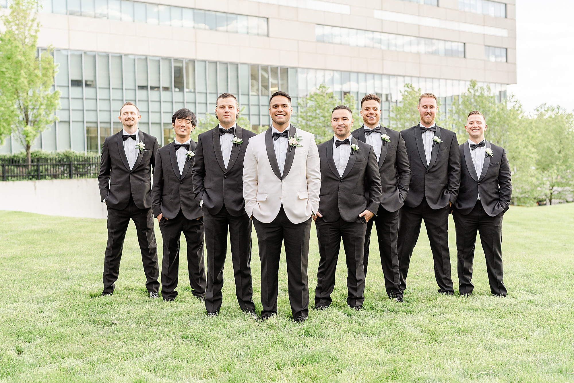 groom poses with groomsmen in white suit jacket