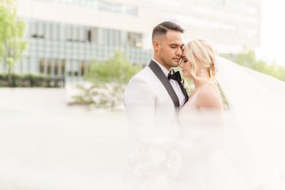 groom leans on bride's forehead with veil wrapped around them