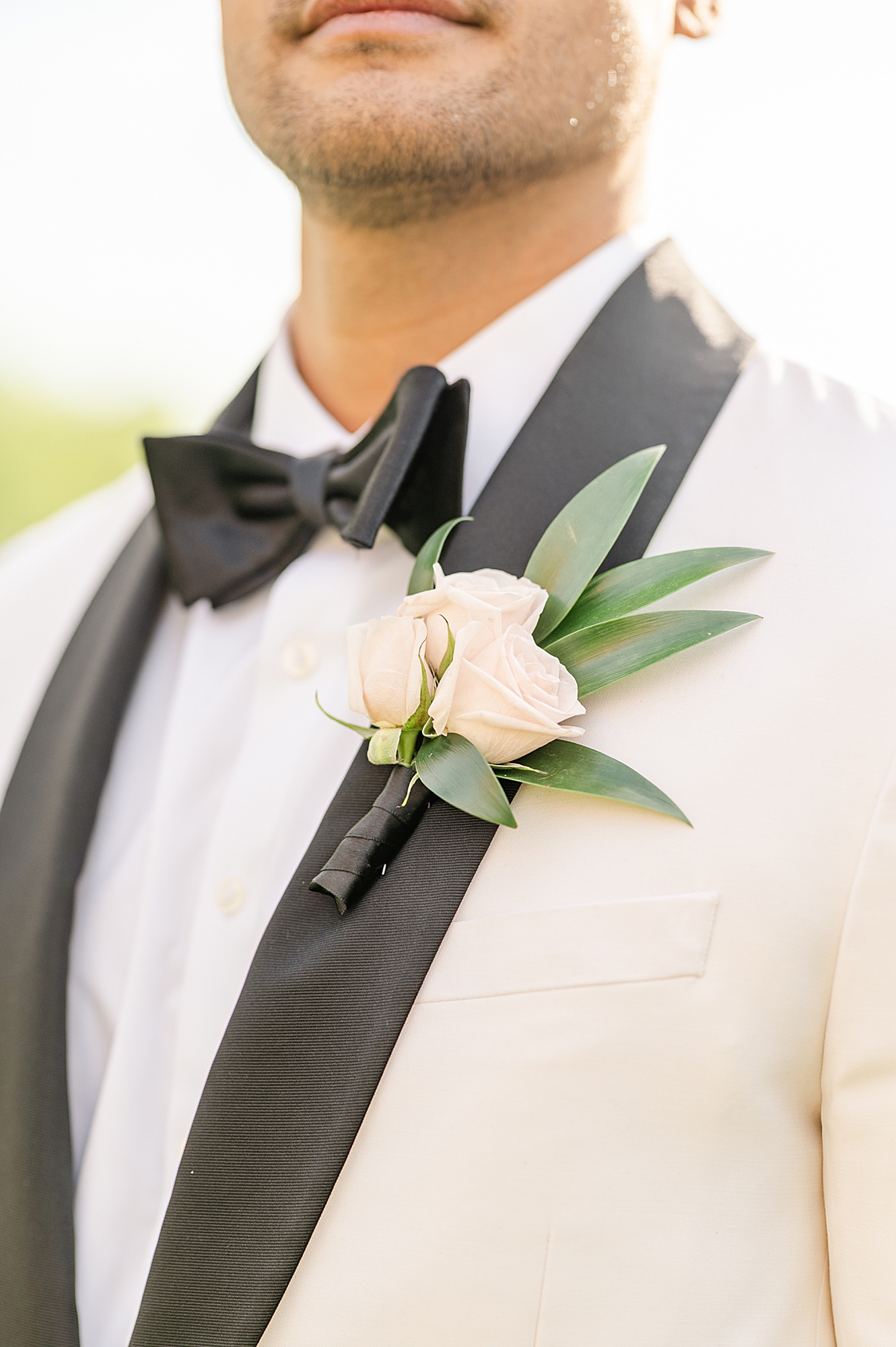 groom in white suit jacket with Ivory rose boutonnière