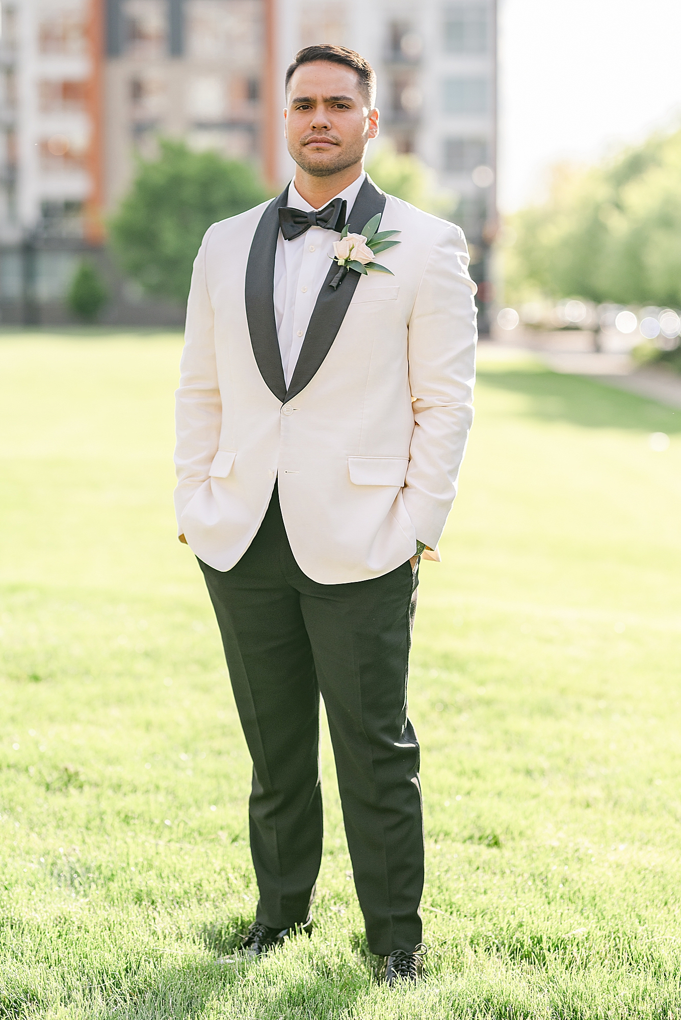 groom in white tux jacket poses outside Westin Southern Columbus
