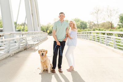 engaged couple poses with dog on bridge in Columbus