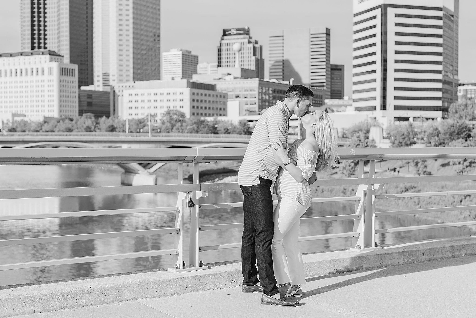engaged couple kisses on bridge in downtown Columbus