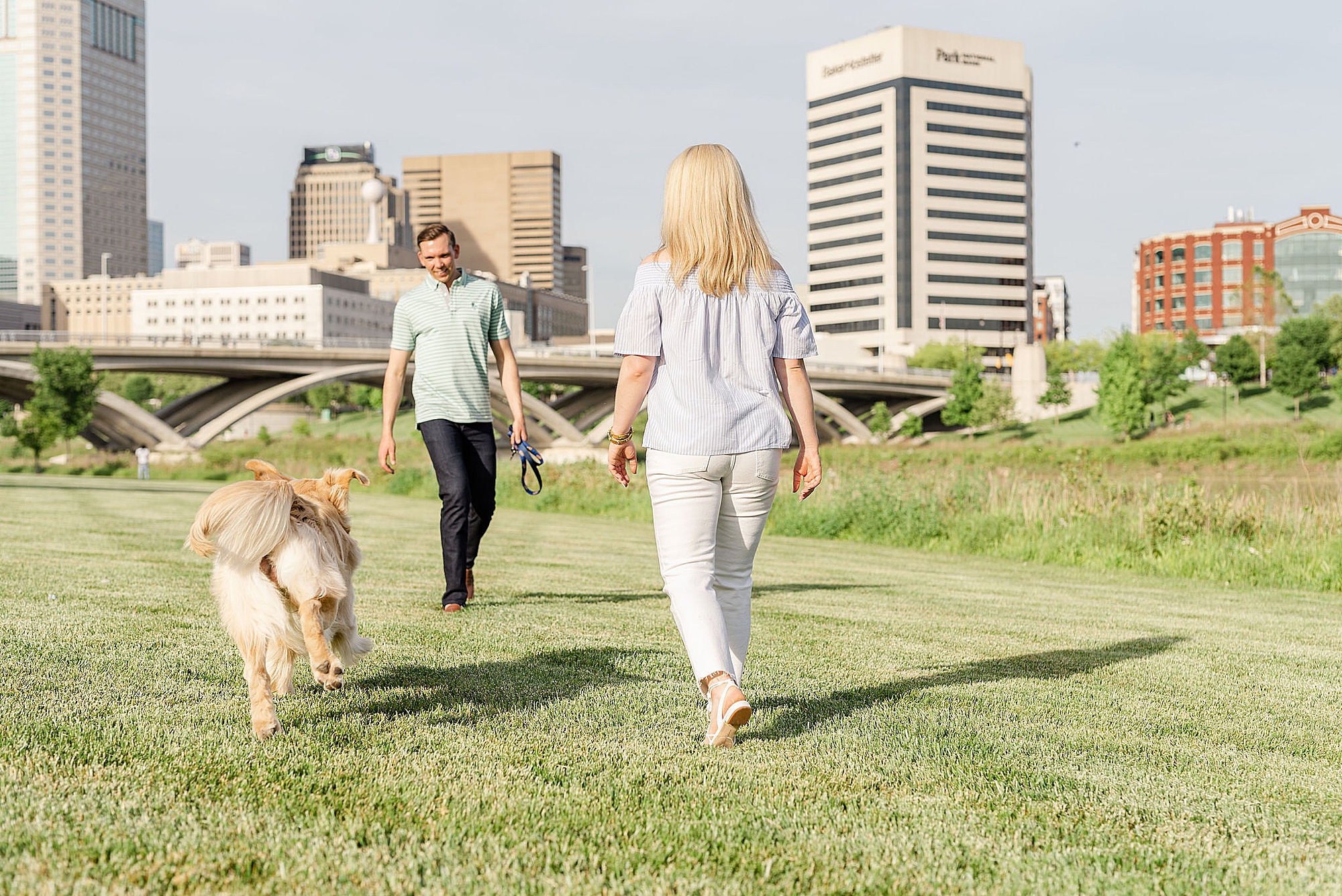 couple plays in park during downtown Columbus engagement photos with dog