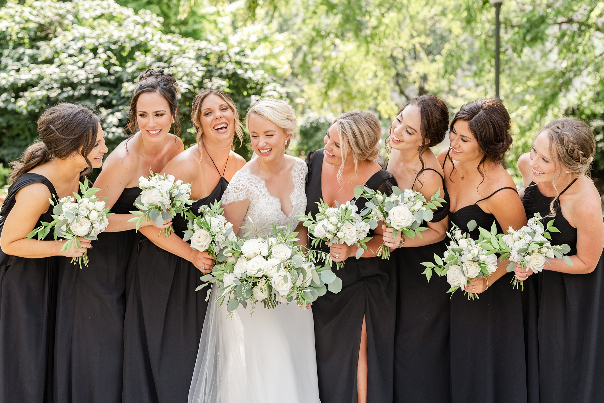 bride laughs with bridesmaids in black dresses
