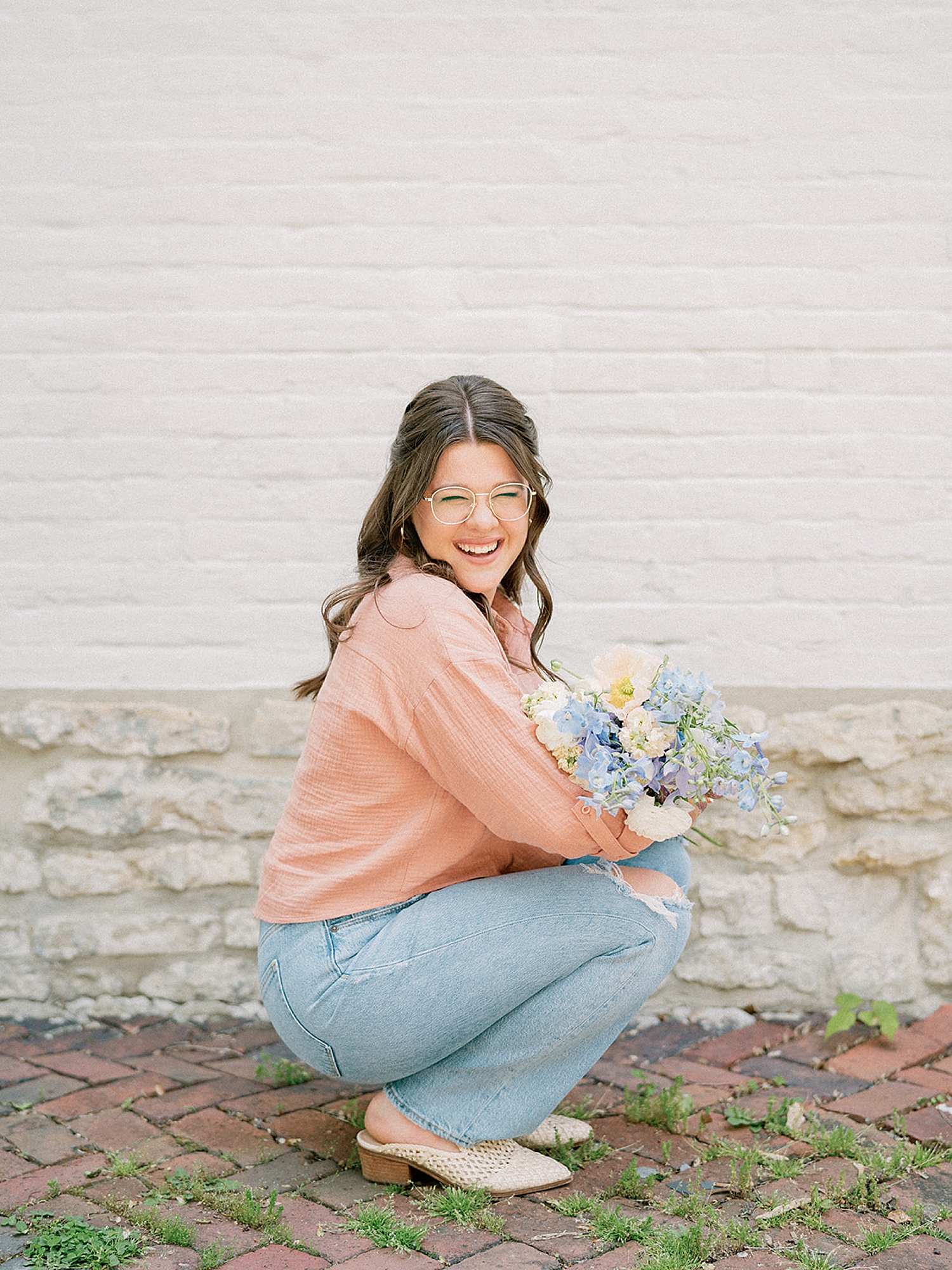 business owner squats down holding flowers during Branding Photoshoot for Online Business Educator