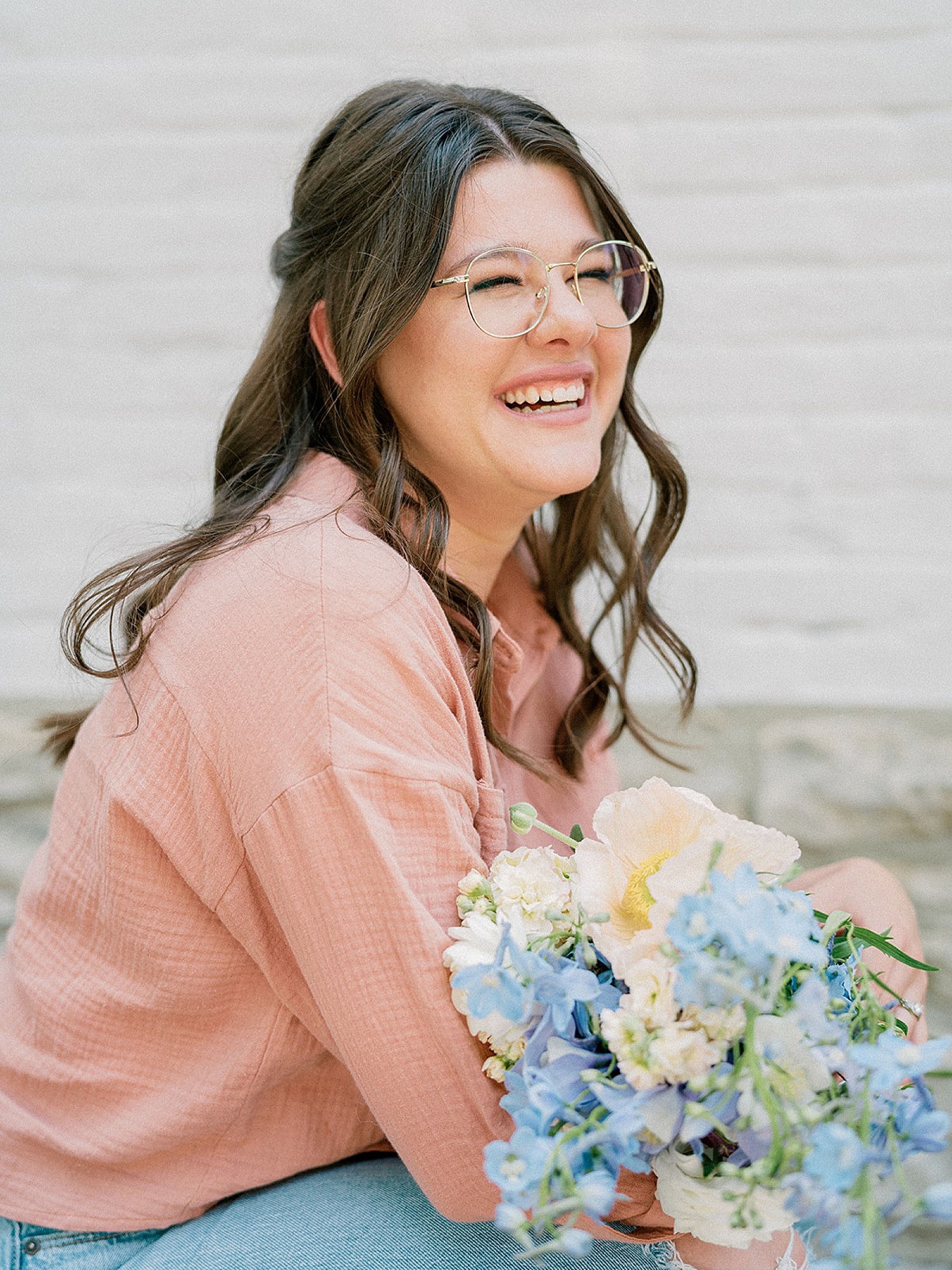 woman laughs holding pink and blue flowers