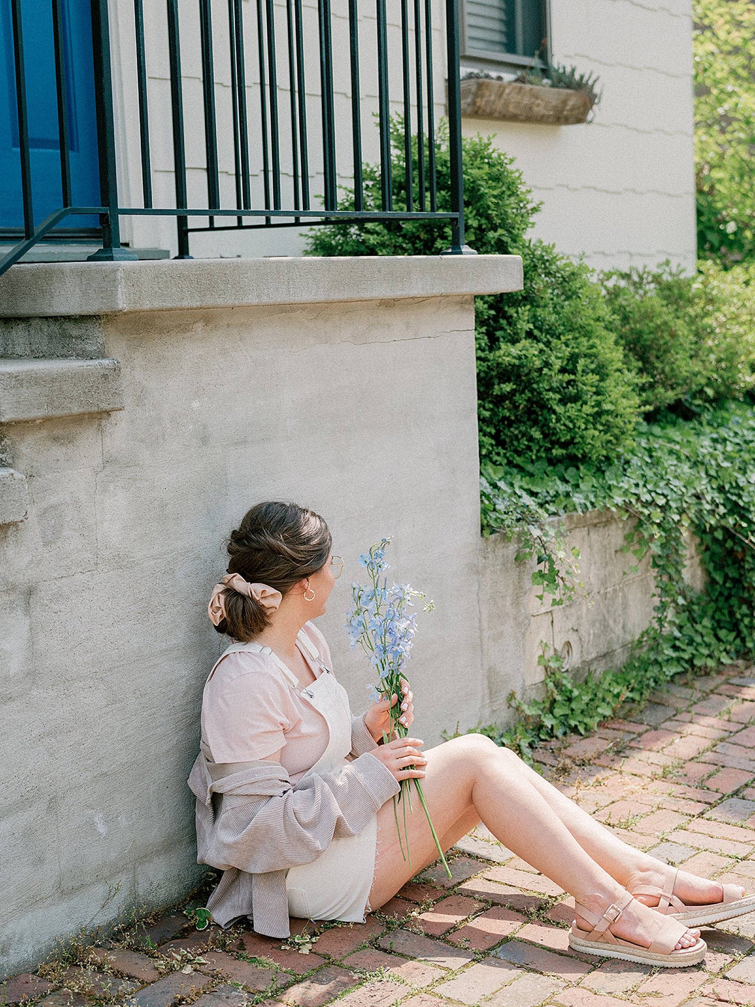 business owners sits by brick wall holding flowers
