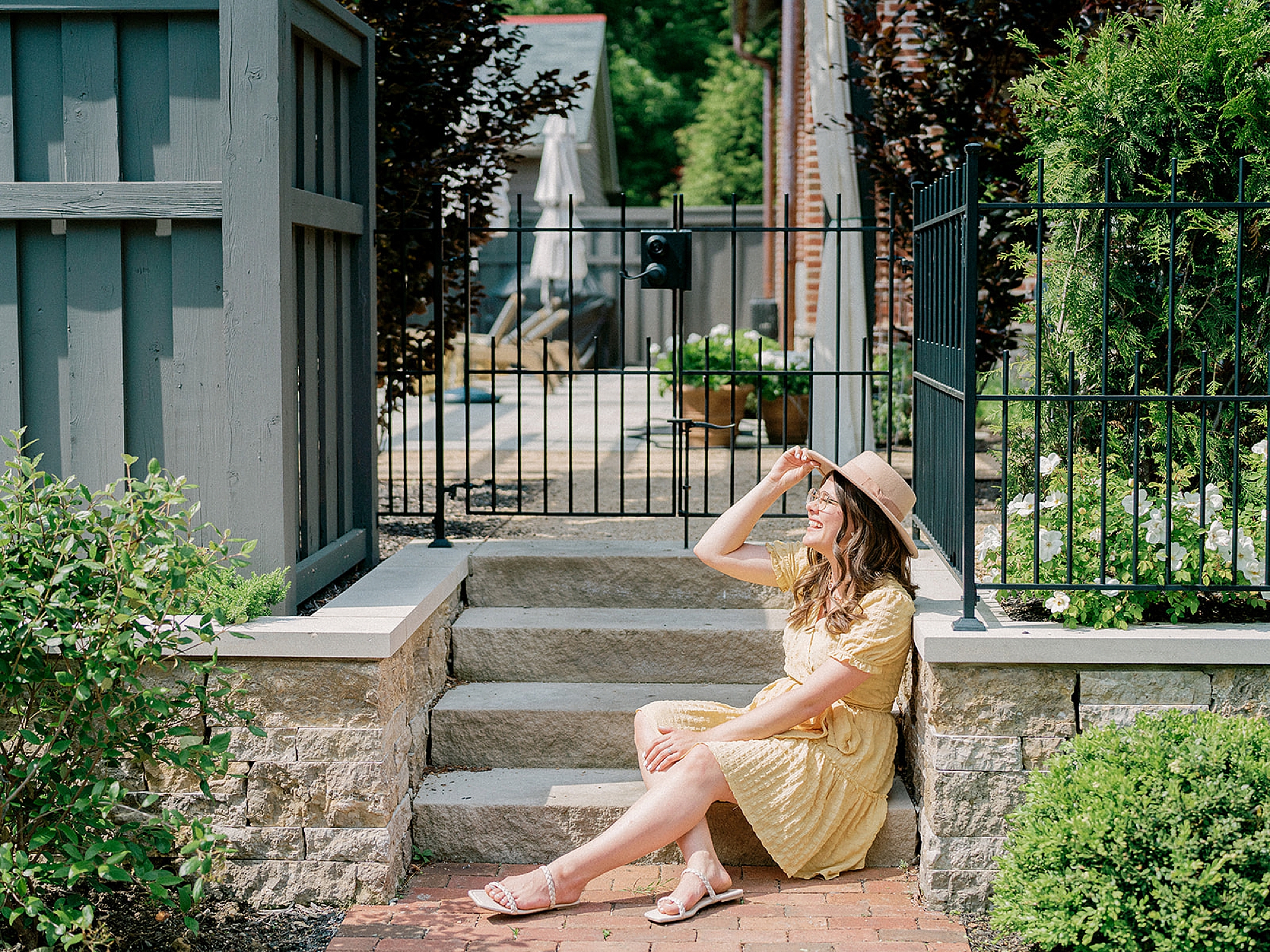 woman sits on steps in wide brimmed hat during branding photos