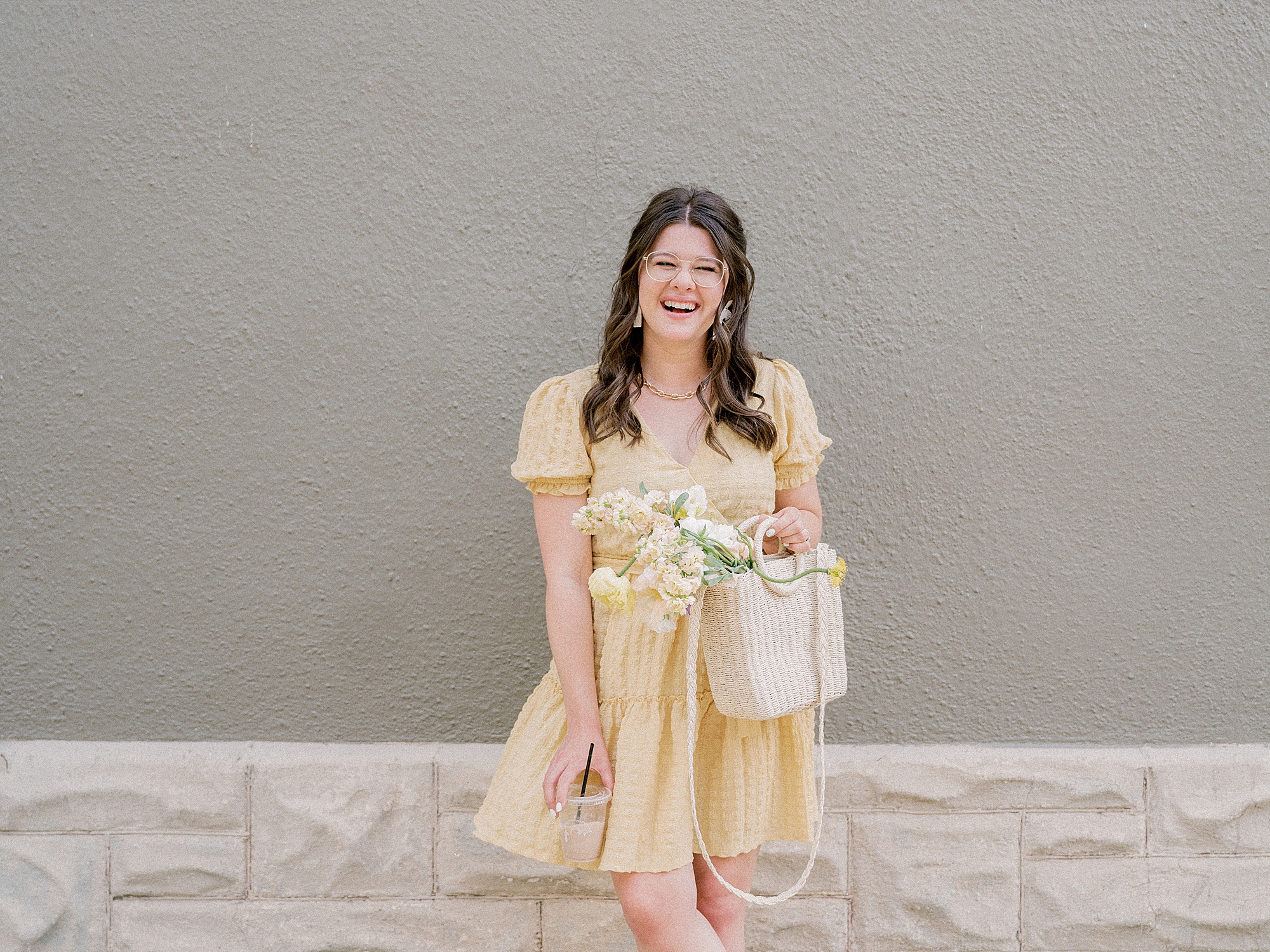woman poses against wall in yellow dress with flowers