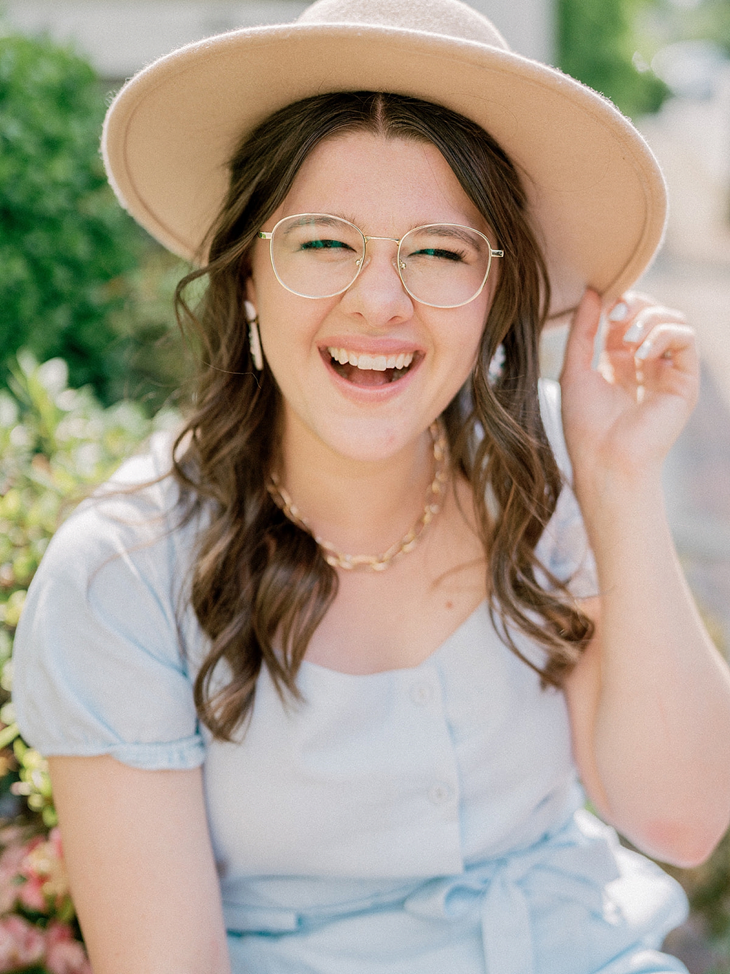 young woman holds wide brimmed hat during branding photos