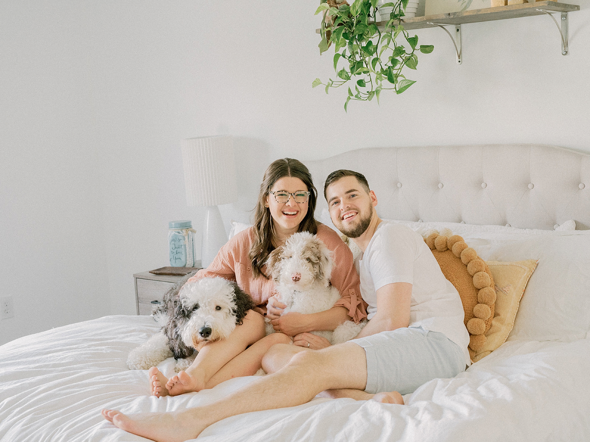 couple sits on bed with two dogs during in-home fourth anniversary portraits