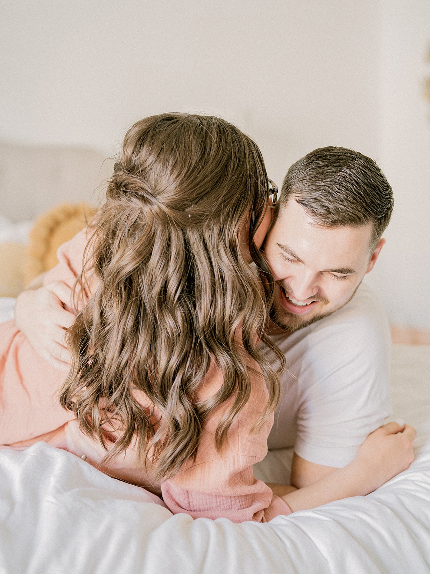 couple cuddles on bed during anniversary photos at home