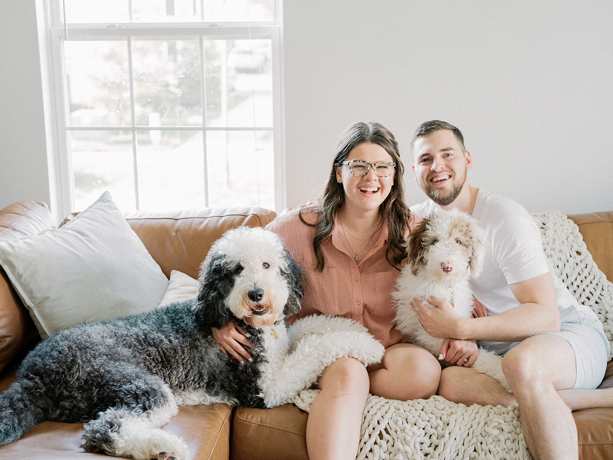 couple sits on couch with two dogs during fourth anniversary portraits