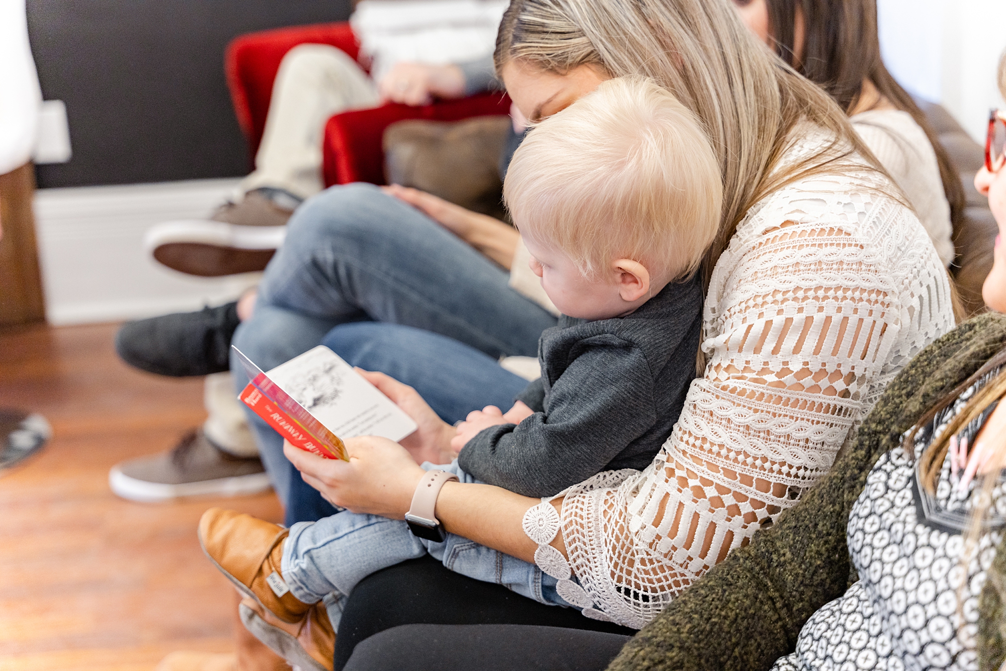 mom reads book with toddler during baby shower