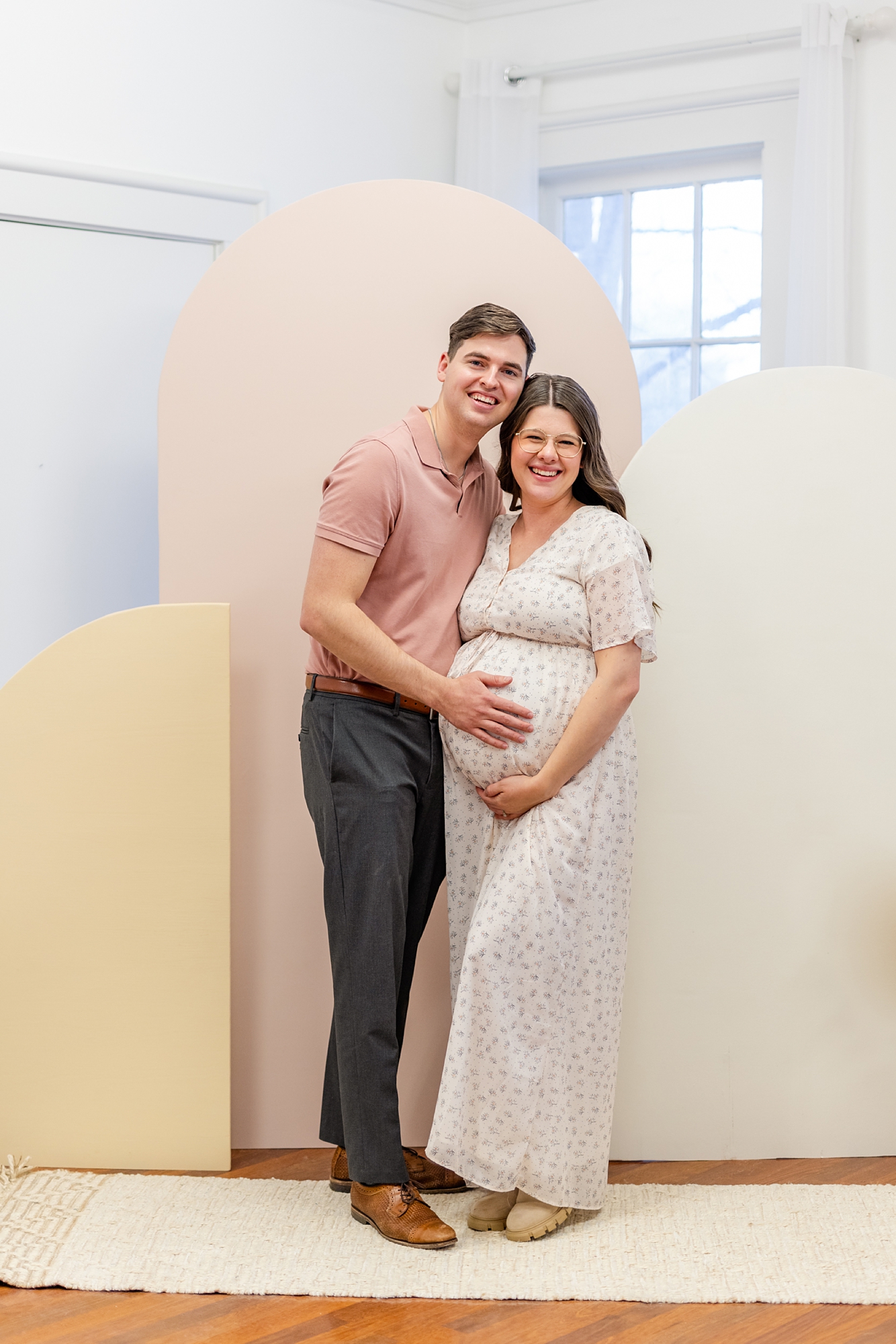 expecting parents pose in front of custom wooden arches during boho blush baby shower