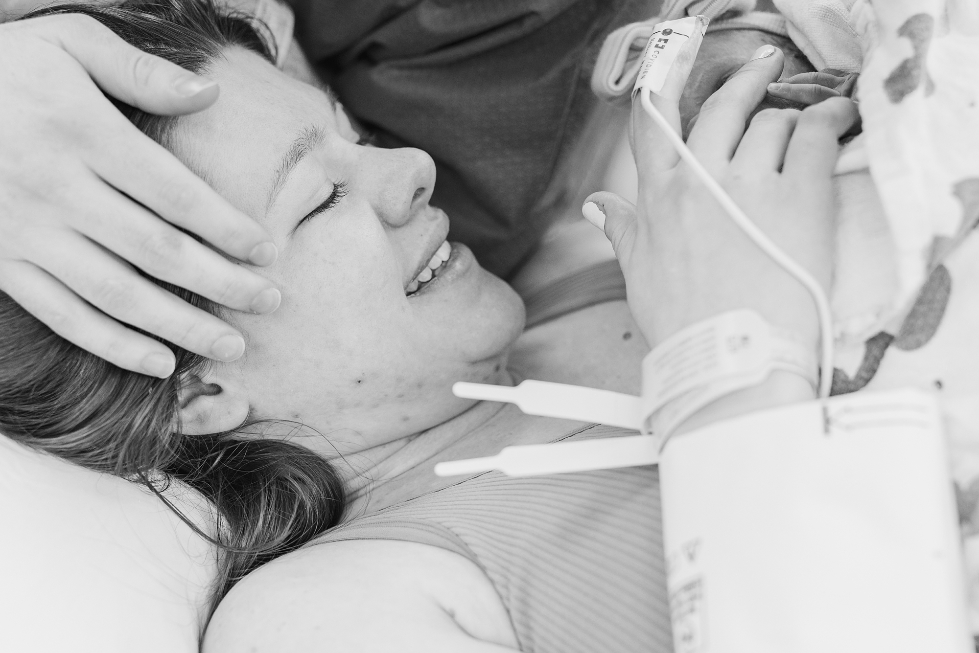 mom smiles holding baby girl after giving birth