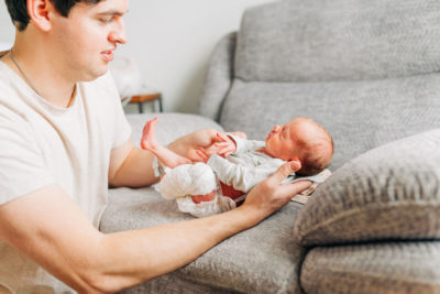 dad holds baby on rocker in nursery