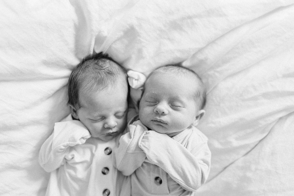 sisters lay on bed together during newborn photos