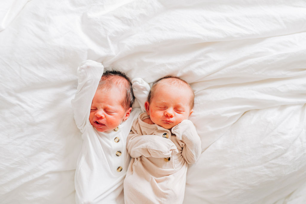 baby girls lay together on bed during newborn session