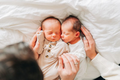 new parents hold twins on bed during newborn session