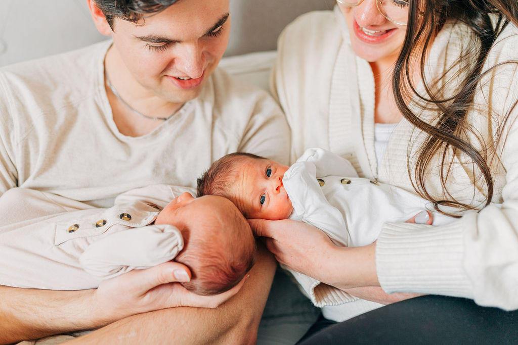 mom and dad hold twins together during newborn photos at home