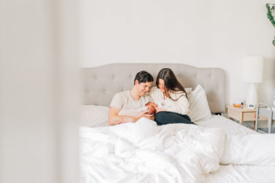 new parents look at baby girls sitting in bed