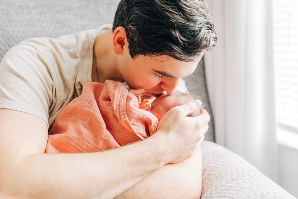 dad kisses baby in pink wrap