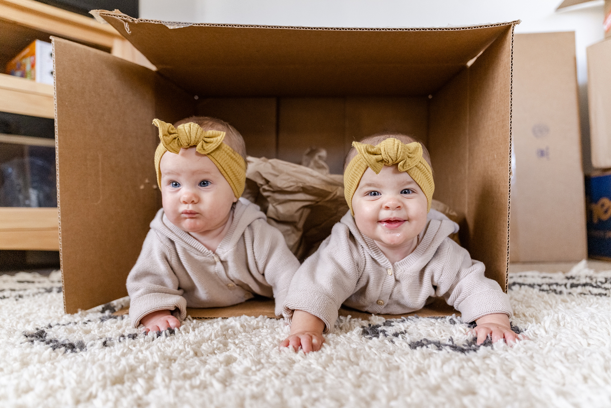 twin girls crawl out of cardboard box